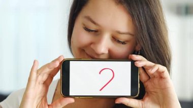 Dünya Sağlık Günü konsepti. Akıllı telefonunda kalp örnekleri gösteren genç bir kadın, kardiyovasküler sağlık bilincinin uluslararası sağlık gözlemi üzerindeki önemini gösteriyor.. 