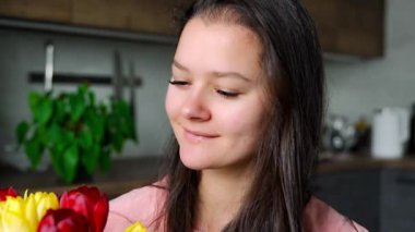 Evde bir buket kırmızı ve sarı lalenin keyfini çıkaran genç bir kadının portresi. Uluslararası Kadınlar Günü 'nü ve Anneler Günü' nü kutlarım. Yüksek kalite 4k görüntü
