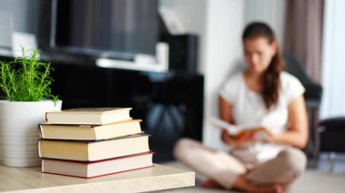 Ön planda kitap yığını ve arka planda kitap okuyan kadın. Yüksek kalite 4k görüntü
