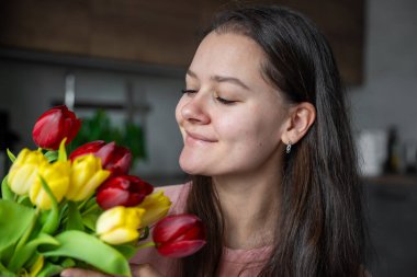 Evinde bir buket kırmızı ve sarı laleli genç bayanın portresi. Uluslararası Kadınlar Günü 'nü ve Anneler Günü' nü kutlarım. Yüksek kalite fotoğraf