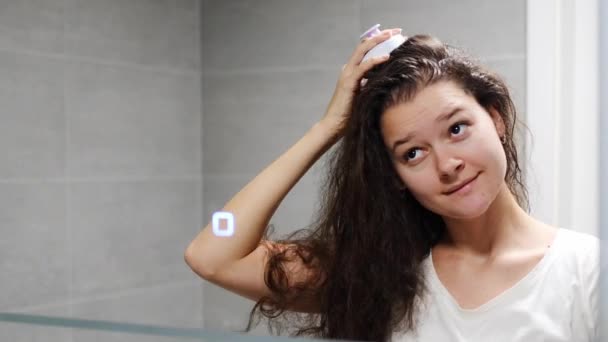 ダークカーリーヘアを持つ若い女性は 自宅のバスルームで刺激的な髪の成長のための頭皮マッサージや髪の成長のためのヘアブラシでセルフヘアスカルプマッサージを行っています 鏡の視点を反映した 高品質の写真 — ストック動画
