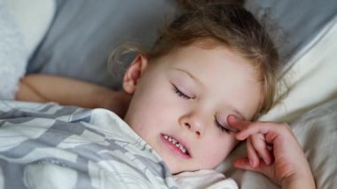 Tatlı küçük kız uyuyor ve rüyalarda dişlerini gıcırdatıyor. Yorgunluk ve stresten dişlerini sıkıyor. Yüksek kalite 4k görüntü