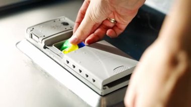 Kadın eli bulaşık makinesine deterjan, çok fonksiyonlu tablet koyuyor. Ev işleri, modern mutfak gereçleri. Yüksek kalite 4k görüntü