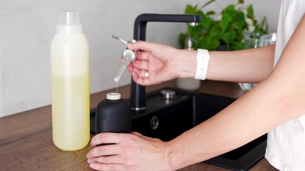一名妇女将回收包装中的肥皂或洗涤剂倒入厨房中可重复使用的瓶子中 生态友好型生活方式概念 高质量的4K镜头 — 图库视频影像
