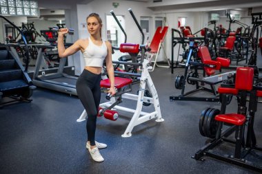 Genç bir kadın elinde dambıllarla spor salonunda egzersiz yapıyor. Yüksek kalite fotoğraf