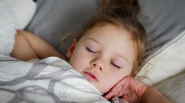 Tatlı küçük kız uyuyor ve rüyalarda dişlerini gıcırdatıyor. Yorgunluk ve stresten dişlerini sıkıyor. Yüksek kalite 4k görüntü