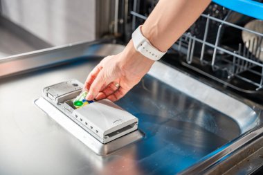 Kadın eli bulaşık makinesine deterjan, çok fonksiyonlu tablet koyuyor. Ev işleri, modern mutfak gereçleri. Yüksek kalite fotoğraf