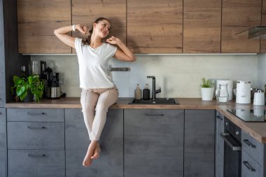 Sabahları genç bir kadın mutfak tezgahında oturuyor. Yüksek kalite fotoğraf