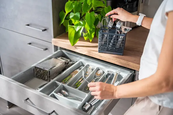 Kadın bir ev hanımı bulaşık makinesinden sonra çatal bıçak takımlarını topluyor. Çatal, kaşık, bıçak aksesuarları depolama organizasyonu için derli toplu bir kadın. Yüksek kalite fotoğraf