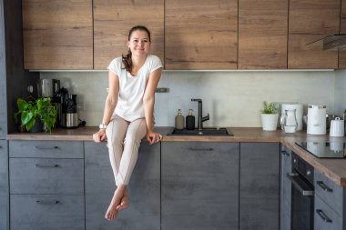 Evde mutfak tezgahında oturan genç bir kadın. Yüksek kalite fotoğraf