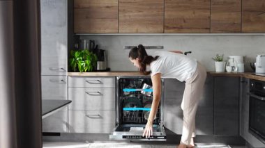 Kadın bulaşık makinesinden temiz seramik tabakları çıkarıyor. Ev ve kullanışlı teknoloji konsepti. Yüksek kalite 4k görüntü