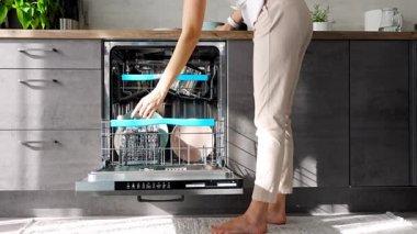 Bulaşık makinesine kirli seramik tabak koyan bir kadın. Ev ve yardımcı teknoloji konsepti. Yüksek kalite 4k görüntü
