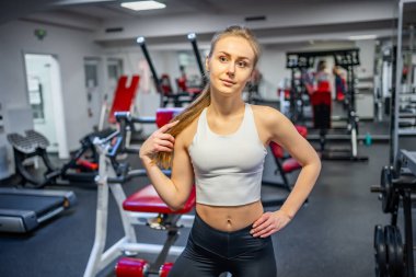 Spor kıyafetleri giyen genç bir kadın spor salonunda spor malzemeleriyle egzersiz yapmadan önce güçlü ve iyi olmak için egzersiz yapıyor. Yüksek kalite fotoğraf