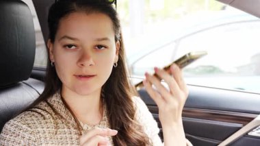 Arabadaki cep telefonundan sesli mesaj dinleyen genç bir kadın. Yüksek kalite 4k görüntü