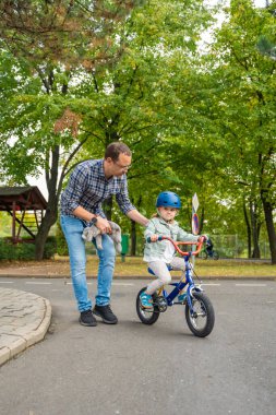 Genç baba, çocuk kızına Prag, Çek Cumhuriyeti, Avrupa 'da trafik parkında bisiklet sürmeyi öğretiyor. Yüksek kalite fotoğraf
