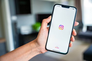 Prag, Çek Cumhuriyeti - 2 Mayıs 2024: Evde mobil uygulama kullanarak ekranda iPhone ve video Instagram 'ı tutan kadın. Yüksek kalite fotoğraf