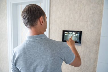 Adam akıllı ev yaşamını kontrol etmek için tablet panel uygulaması kullanıyor. Duvarda ev otomasyonu için kablosuz cihaz kontrolörü var. Yüksek kalite fotoğraf