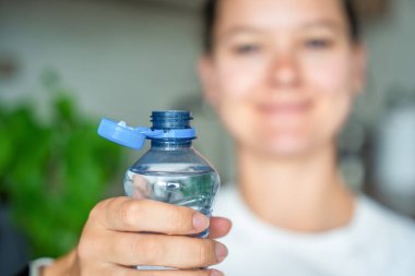 Kadın elinde plastik kapaklı bir şişe. Yeni tasarım, kapağın açıldıktan sonra şişeye bağlı kalması ve tüm paketin toplanıp geri dönüşümünün kolaylaştırılması anlamına geliyor. Yüksek kalite fotoğraf
