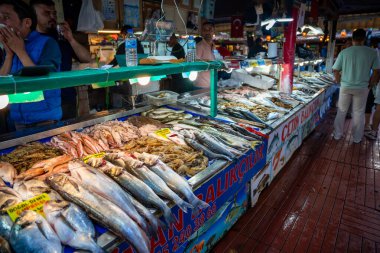 Fethiye, Türkiye - 11 Mayıs 2024: Türkiye 'de eski kentin Fathiye Balık Pazarı' nı taze deniz ürünleri ve restoranları ile birlikte insanlar ziyaret ediyor. Yüksek kalite fotoğraf