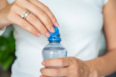 Kadın elinde plastik kapaklı bir şişe. Yeni tasarım, kapağın açıldıktan sonra şişeye bağlı kalması ve tüm paketin toplanıp geri dönüşümünün kolaylaştırılması anlamına geliyor. Yüksek kalite fotoğraf