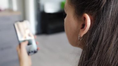 Genç bir kadın sosyal medya hesaplarını karıştırıyor ve evde otururken video izliyor. Yüksek kalite 4k görüntü