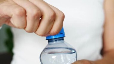Kadın elinde plastik kapaklı bir şişe. Yeni tasarım, kapağın açıldıktan sonra şişeye bağlı kalması ve tüm paketin toplanıp geri dönüşümünün kolaylaştırılması anlamına geliyor. 4k görüntü