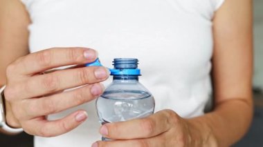 Kadın elinde plastik kapaklı bir şişe. Yeni tasarım, kapağın açıldıktan sonra şişeye bağlı kalması ve tüm paketin toplanıp geri dönüşümünün kolaylaştırılması anlamına geliyor. 4k görüntü