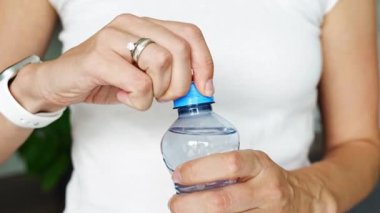 Kadın elinde plastik kapaklı bir şişe. Yeni tasarım, kapağın açıldıktan sonra şişeye bağlı kalması ve tüm paketin toplanıp geri dönüşümünün kolaylaştırılması anlamına geliyor. 4k görüntü