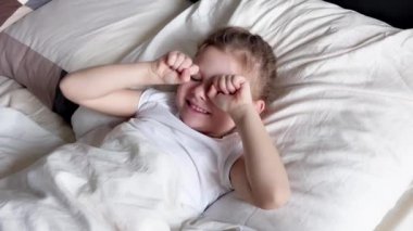 Sevimli küçük kız, şekerleme yaptıktan sonra yatağında uyandığı için gülümseyerek kollarını uzatıyordu. Yüksek kalite 4k görüntü