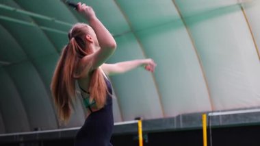 Raket ve mekikle spor yapan genç bir kadın spor yapıyor, iç sahada badminton oynuyor. Yüksek kalite 4k görüntü