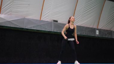 Raket ve mekikle spor yapan genç bir kadın spor yapıyor, iç sahada badminton oynuyor. Yüksek kalite 4k görüntü