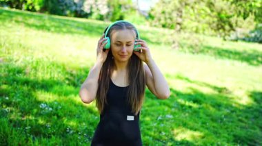 Kablosuz kulaklık takan genç bir kadın şehir parkında müzik dinliyor. Yüksek kalite 4k görüntü