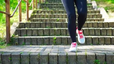 Merdivenlerden koşarak çıkan genç bir kadının bacaklarına yakından bakın. Şehir parkındaki merdivenlerde koşu egzersizi yapıyor. Yüksek kalite 4k görüntü