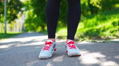 Siyah spor giysili genç bir kadın şehir parkında ayak ve bacak egzersizleri yapıyor. Koşmadan ya da koşmadan önce ısın. Açık hava sporları eğitimi konsepti. Yüksek kalite 4k görüntü