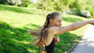 Genç, formda, sporcu bir kadın parkta boks yapıyor. Açık hava sporları eğitimi konsepti. Yüksek kalite 4k görüntü