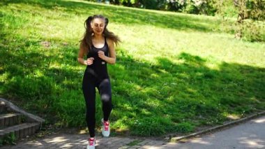 Genç sporcu kadın parkta koşuyor. Dış konseptte spor yapan kadın. Yüksek kalite 4k görüntü