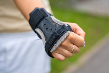 Parkta paten kayan patenci kadının koruma eldivenindeki el görüntüsünü kapat. Açık hava aktiviteleri. Yaz pateni. Yüksek kalite fotoğraf