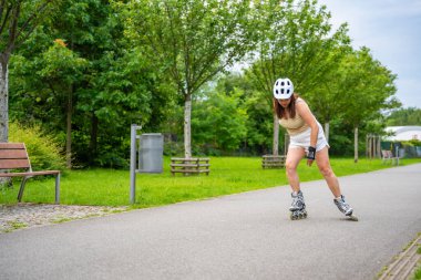 Parktaki patenci kadın paten kayıyor, paten kayıyor. Açık hava aktiviteleri. Yaz pateni. Yüksek kalite fotoğraf
