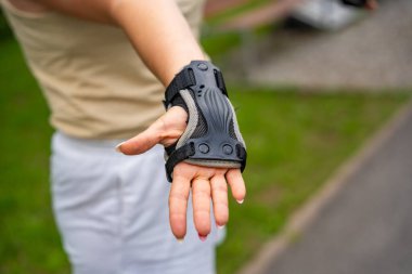 Parkta paten kayan patenci kadının koruma eldivenindeki el görüntüsünü kapat. Açık hava aktiviteleri. Yaz pateni. Yüksek kalite fotoğraf