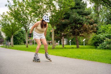 Parktaki patenci kadın paten kayıyor, paten kayıyor. Açık hava aktiviteleri. Yaz pateni. Yüksek kalite fotoğraf