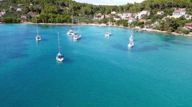Hırvatistan 'ın Korcula adasındaki Vela Luka kasabası yakınlarındaki Uvala Gradina körfezindeki şamandıralara demirlemiş yatların insansız hava aracı görüntüsü. Yüksek kalite 4k görüntü