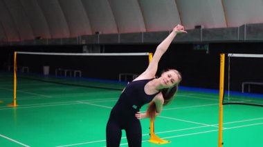 Raket ve mekik aletli genç bayan badminton oynamadan önce antrenman yapıyor, ısınıyor. Yüksek kalite 4k görüntü