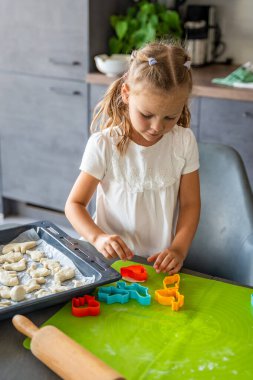 Ev mutfağında hayvan şekilli kesicilerle hamur ile kurabiye yapan küçük bir kız. Aile kavramı. Yüksek kalite fotoğraf