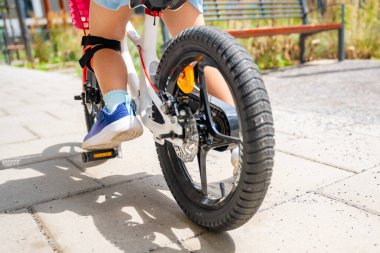 Küçük kız bacaklarının yakın görüntüsü iki tekerlekli bisiklet sürüyor. Yazın, Avrupa 'da apartman binalarının avlusunda. Yüksek kalite fotoğraf
