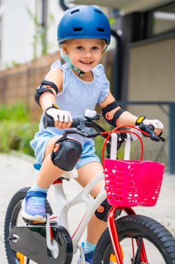 Küçük bir kızın portresi iki tekerlekli bir bisiklete biniyor. Yazın, Avrupa 'da apartmanların avlusunda. Yüksek kalite fotoğraf
