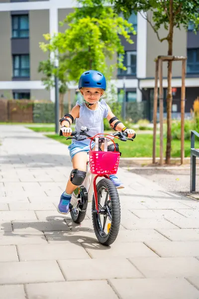 Küçük kız yazın Avrupa 'daki apartmanların avlusunda iki tekerlekli bisiklet sürüyor. Yüksek kalite fotoğraf