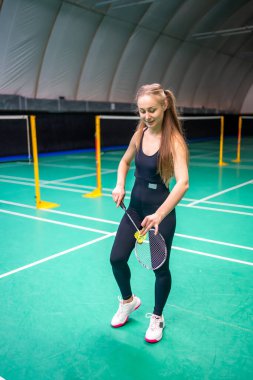 Raket ve servis horozlu genç bayan badminton oynamadan önce iç sahada servis çalışması yapıyor. Yüksek kalite fotoğraf