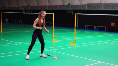 Raket ve mekik aletli genç bayan badminton oynamadan önce antrenman yapıyor, ısınıyor. Yüksek kalite 4k görüntü