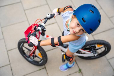 Küçük kızın manzarası yazın, Avrupa 'da, apartmanların avlusunda iki tekerlekli bisiklet sürüyor. Yüksek kalite fotoğraf