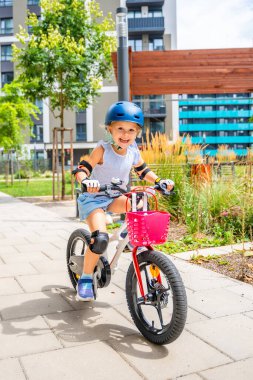 Küçük kız yazın Avrupa 'daki apartmanların avlusunda iki tekerlekli bisiklet sürüyor. Yüksek kalite fotoğraf
